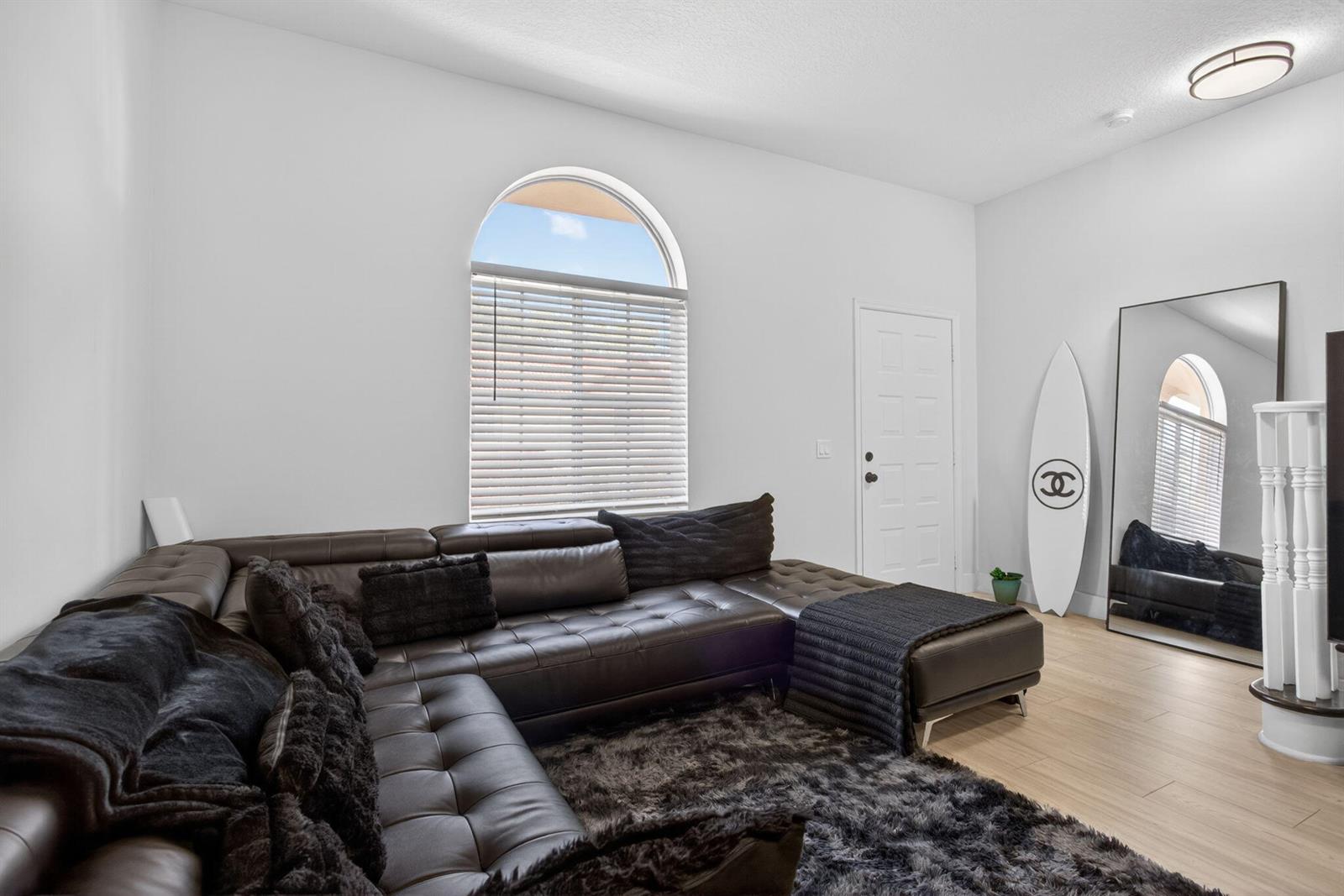 A living room features a dark leather sectional, a shag rug, and a surfboard decoration — 2457 NE 14th Street # 2457, Pompano Beach FL 33062, POMPANO BEACH, FL