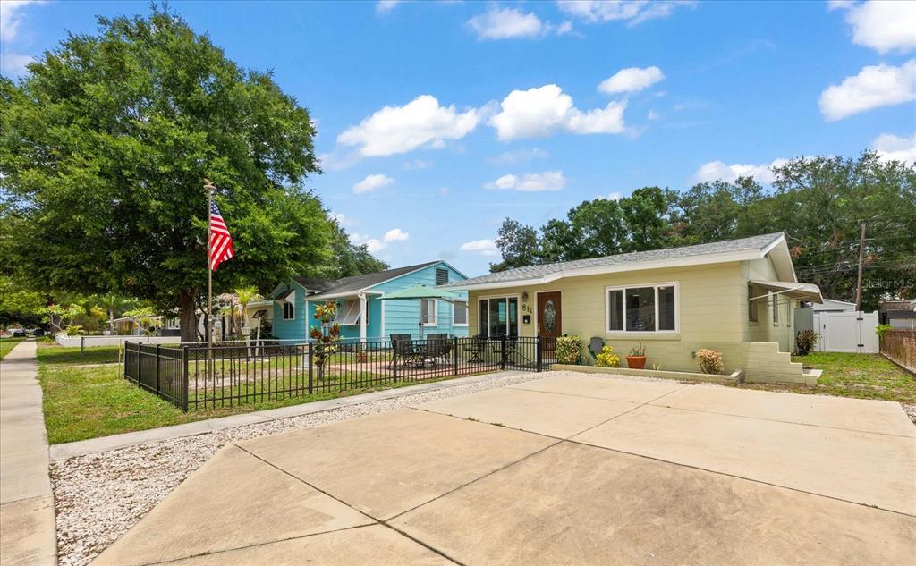 A light green single-story house with a concrete driveway and a black metal front fence — 811 48TH AVENUE N, ST PETERSBURG, FL