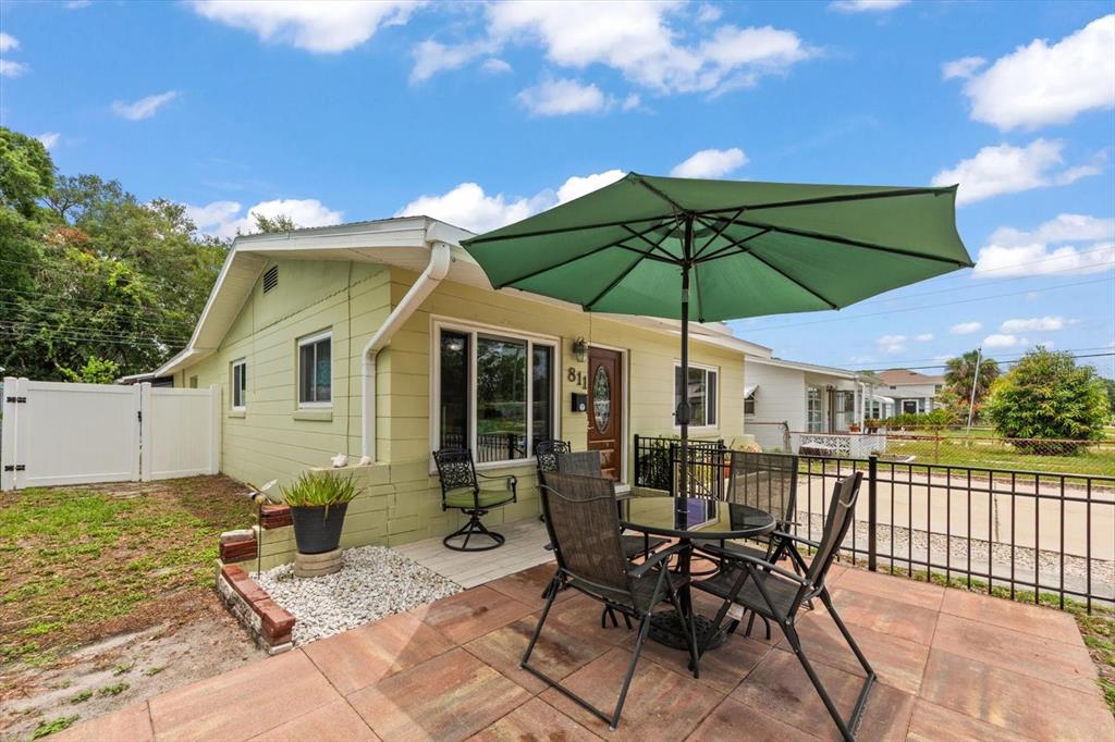 A light green house with a patio, outdoor dining set, and a large green umbrella — 811 48TH AVENUE N, ST PETERSBURG, FL
