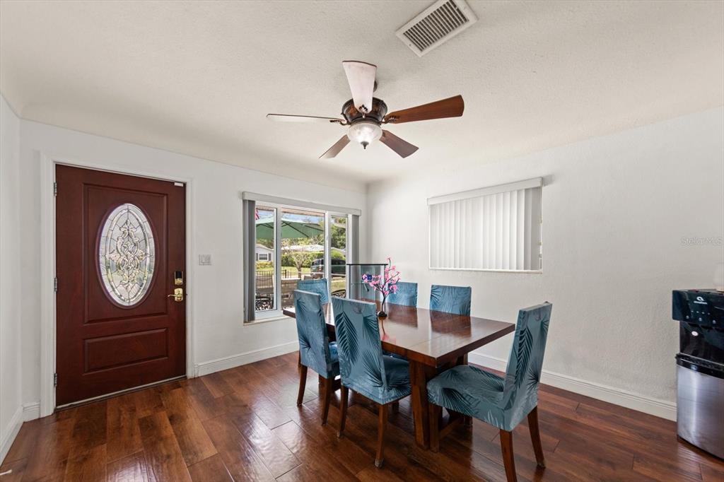 A dining room features a wooden table, blue patterned chairs, hardwood floors, and a front door — 811 48TH AVENUE N, ST PETERSBURG, FL