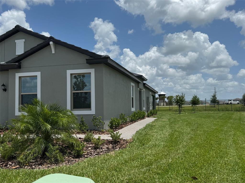 A gray house exterior features a paved walkway, landscaping, and a fenced backyard — 32040 GRIFFIN SANDS LN, SAN ANTONIO, FL