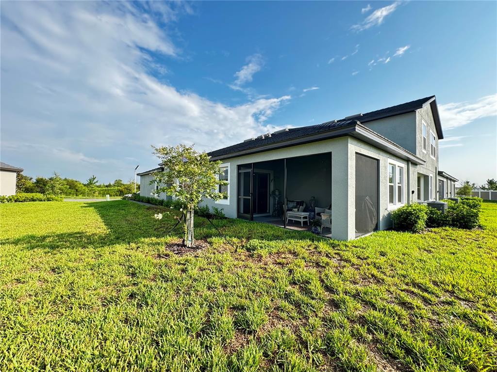 The exterior of a house features a screened-in patio and a small tree in the yard — 32040 GRIFFIN SANDS LN, SAN ANTONIO, FL