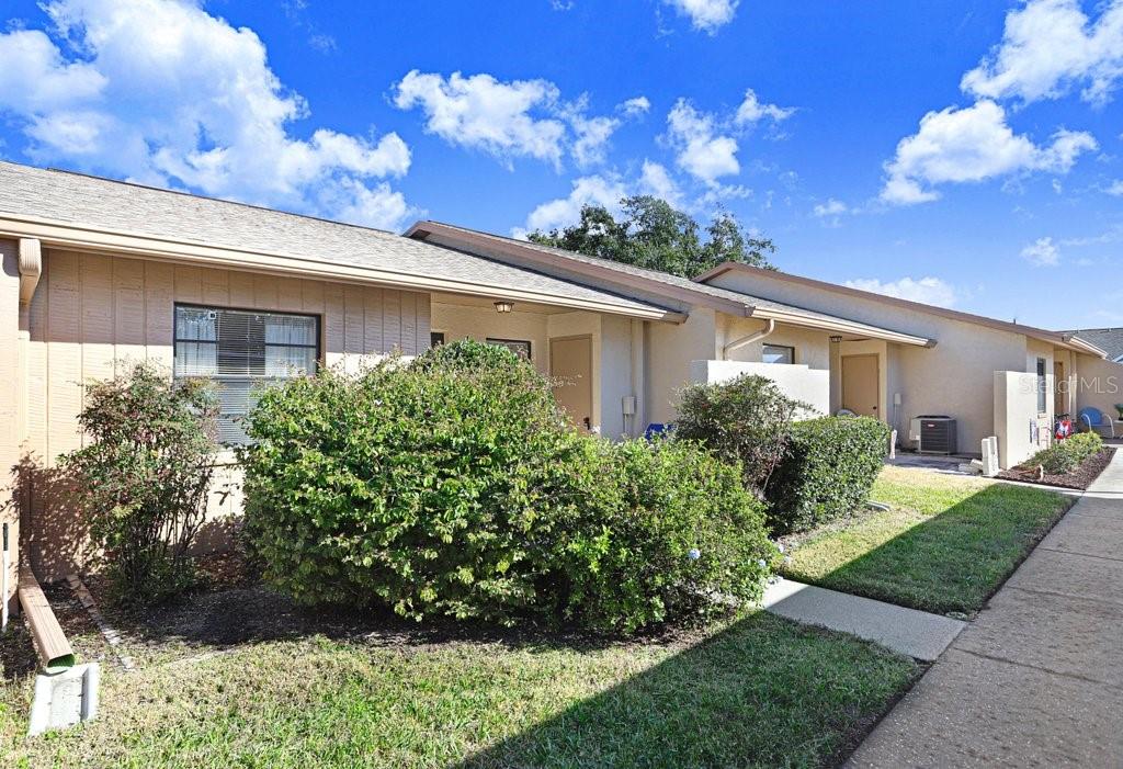 A tan, single-story residential building with a sidewalk and landscaping in front — 38429 COTTONWOOD PLACE, ZEPHYRHILLS, FL