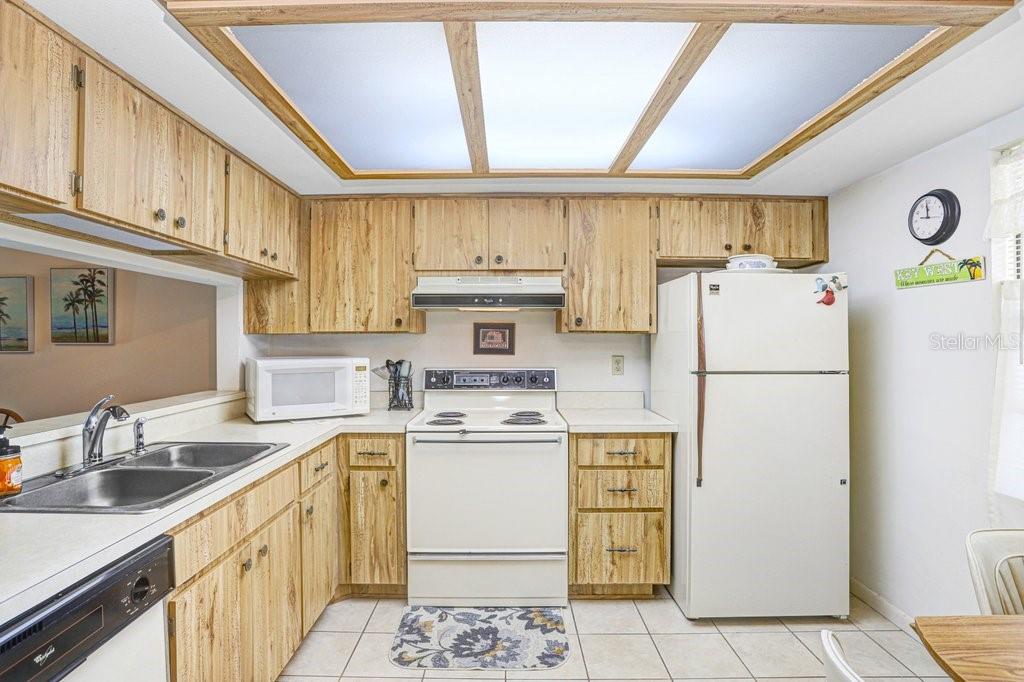 A kitchen with light wood cabinets, white appliances, a double sink, and a drop ceiling — 38429 COTTONWOOD PLACE, ZEPHYRHILLS, FL