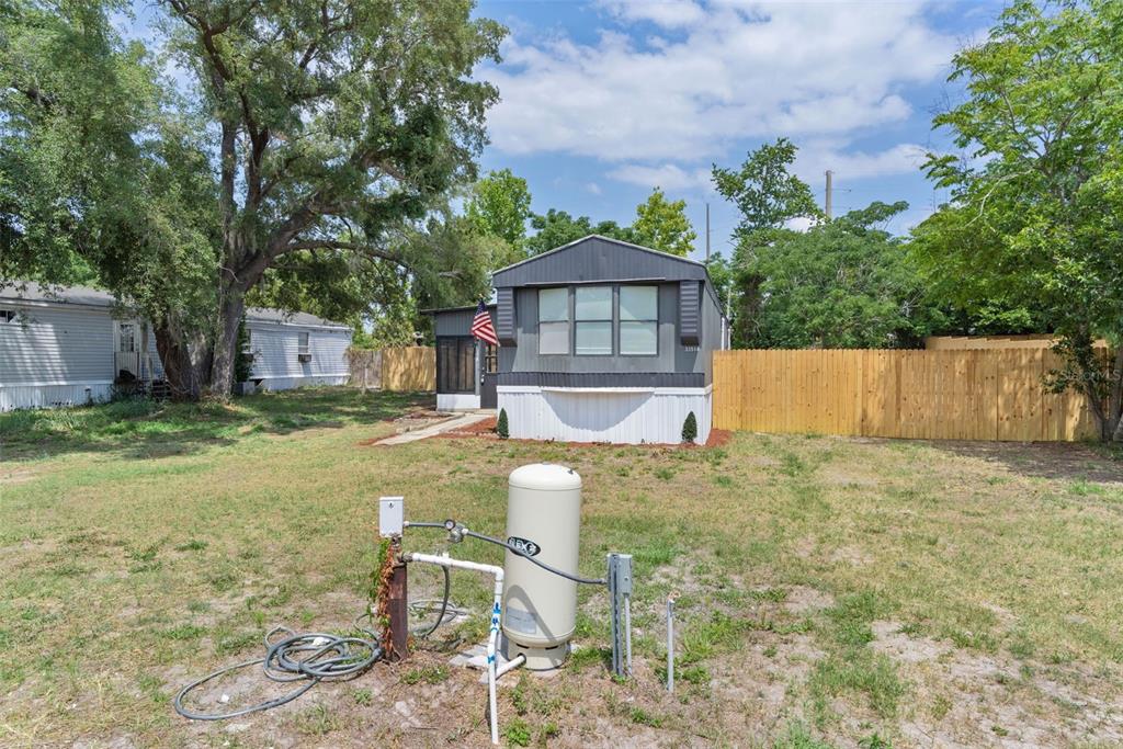 A manufactured home sits on a grassy lot with a well pump and pressure tank — 33514 LUANA COURT, LEESBURG, FL