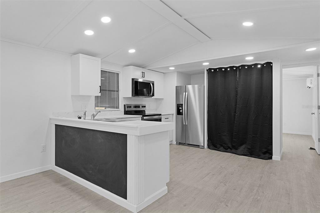 A modern kitchen features white cabinets, stainless steel appliances, and a black chalkboard breakfast bar — 33514 LUANA COURT, LEESBURG, FL