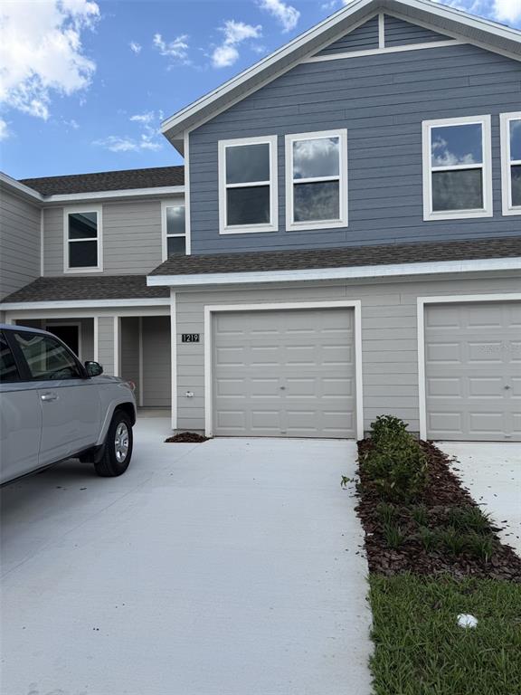 A two-story townhouse exterior features gray siding, a two-car garage, and a concrete driveway — 1219 ORION STREET, DAVENPORT, FL