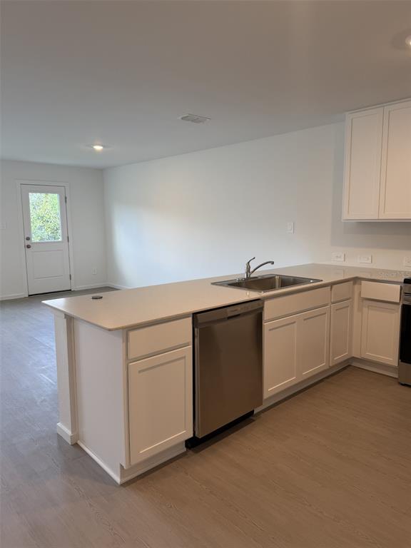 A kitchen features white cabinets, a stainless steel dishwasher, and a sink on a peninsula — 1219 ORION STREET, DAVENPORT, FL
