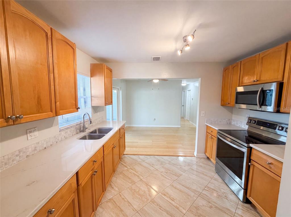 A kitchen with wood cabinets, stainless steel appliances, and light-colored countertops and tile flooring — 8283 86TH AVENUE, SEMINOLE, FL