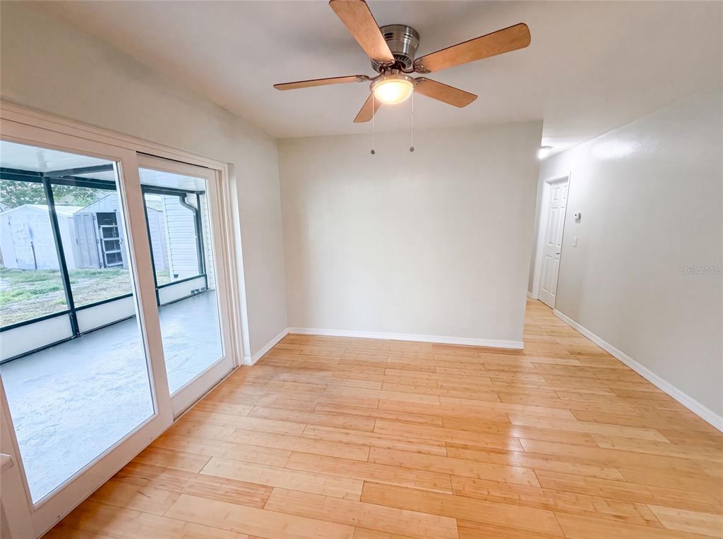 An empty room features light wood flooring, a ceiling fan, and sliding glass doors — 8283 86TH AVENUE, SEMINOLE, FL