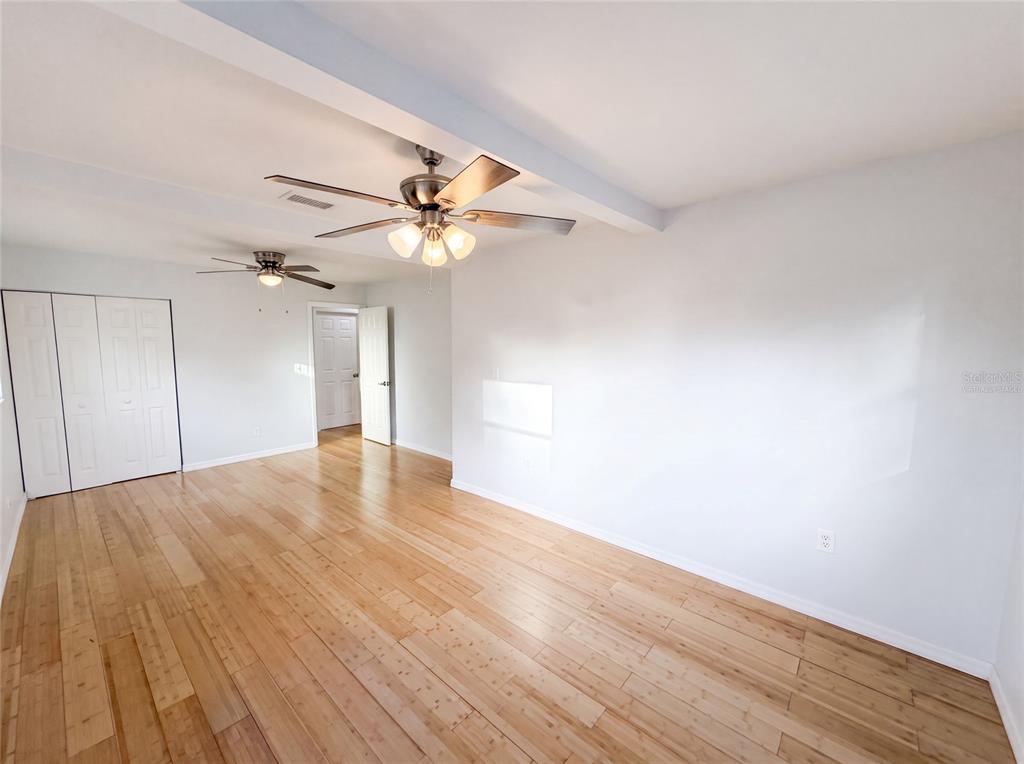 An empty room features light wood flooring, white walls, and two ceiling fans — 8283 86TH AVENUE, SEMINOLE, FL