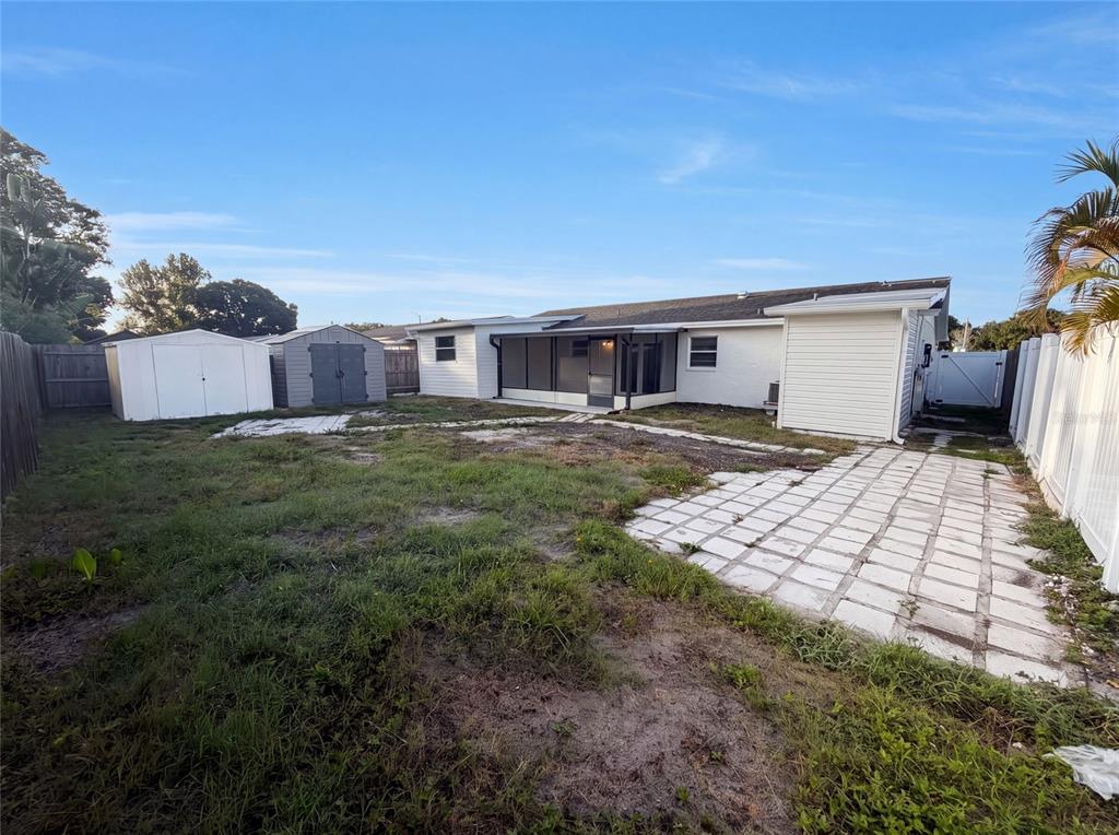 The backyard features a paved patio, a screened-in porch, and two storage sheds — 8283 86TH AVENUE, SEMINOLE, FL