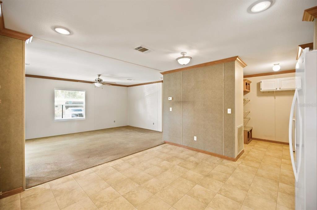 A room with tiled flooring transitions into a carpeted living area with a ceiling fan — 22925 SW 117TH STREET, DUNNELLON, FL