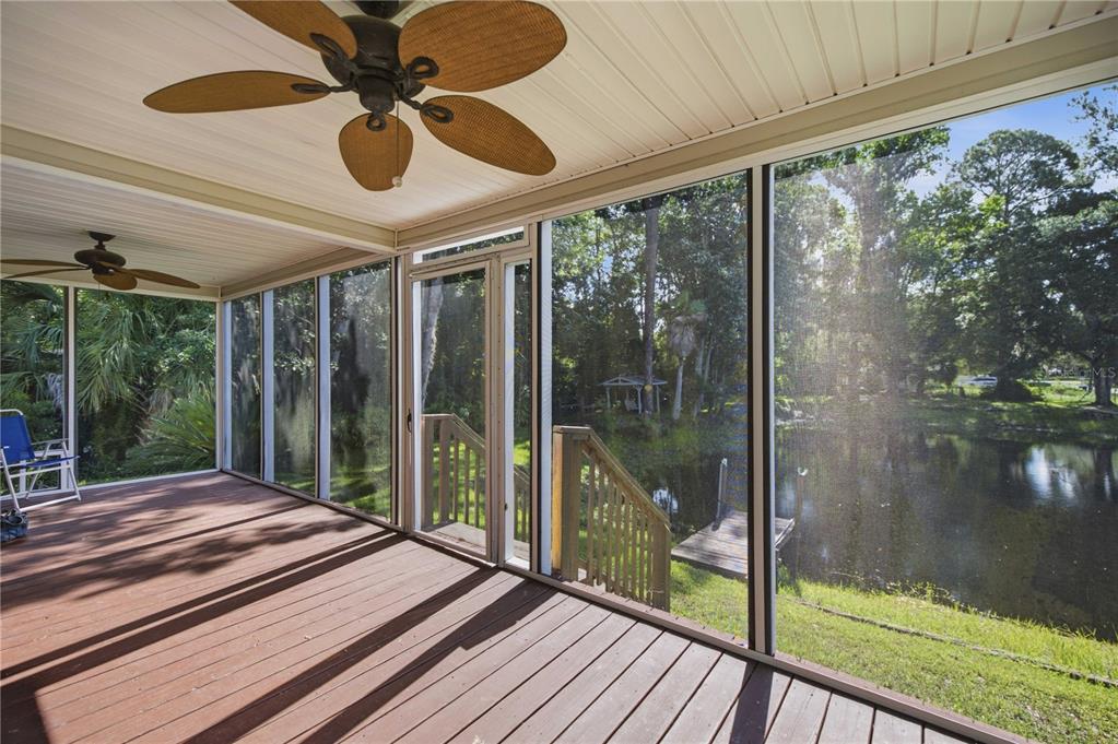 A screened-in porch with wooden decking, ceiling fans, and a view of a pond — 22925 SW 117TH STREET, DUNNELLON, FL