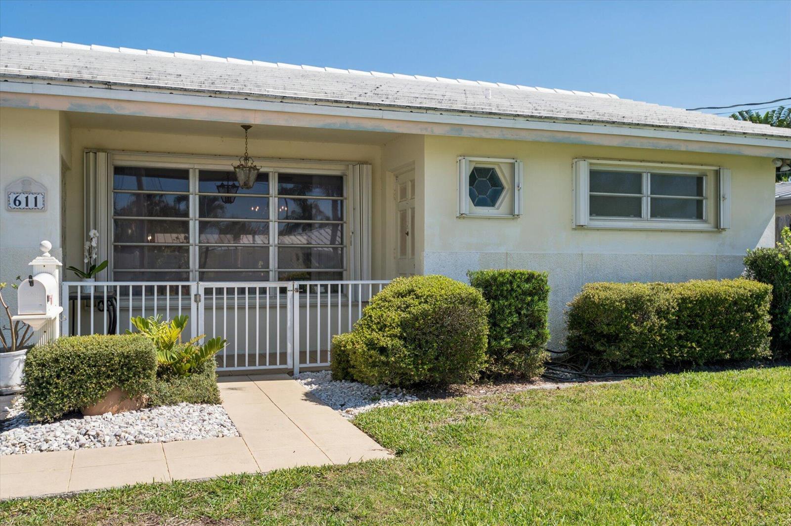 A single-story house with a white exterior, a gated front porch, and manicured landscaping — 611 SE 11th Street, Pompano Beach FL 33060, POMPANO BEACH, FL