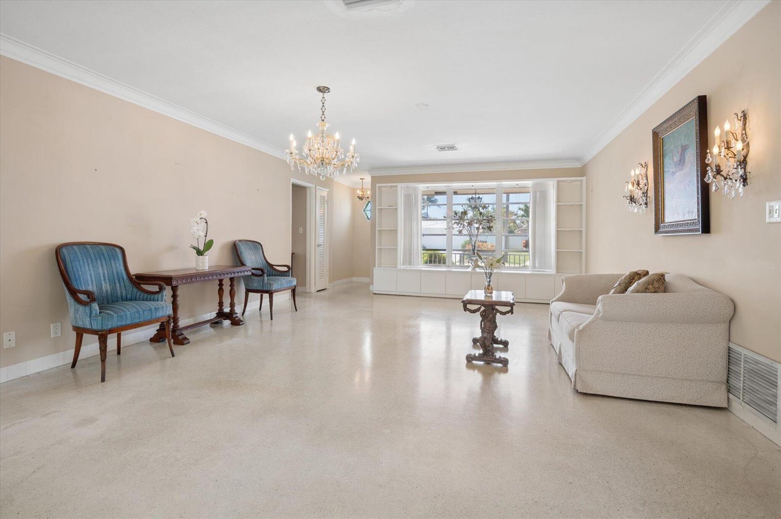 A living room with beige walls, a crystal chandelier, blue chairs, and a white sofa — 611 SE 11th Street, Pompano Beach FL 33060, POMPANO BEACH, FL