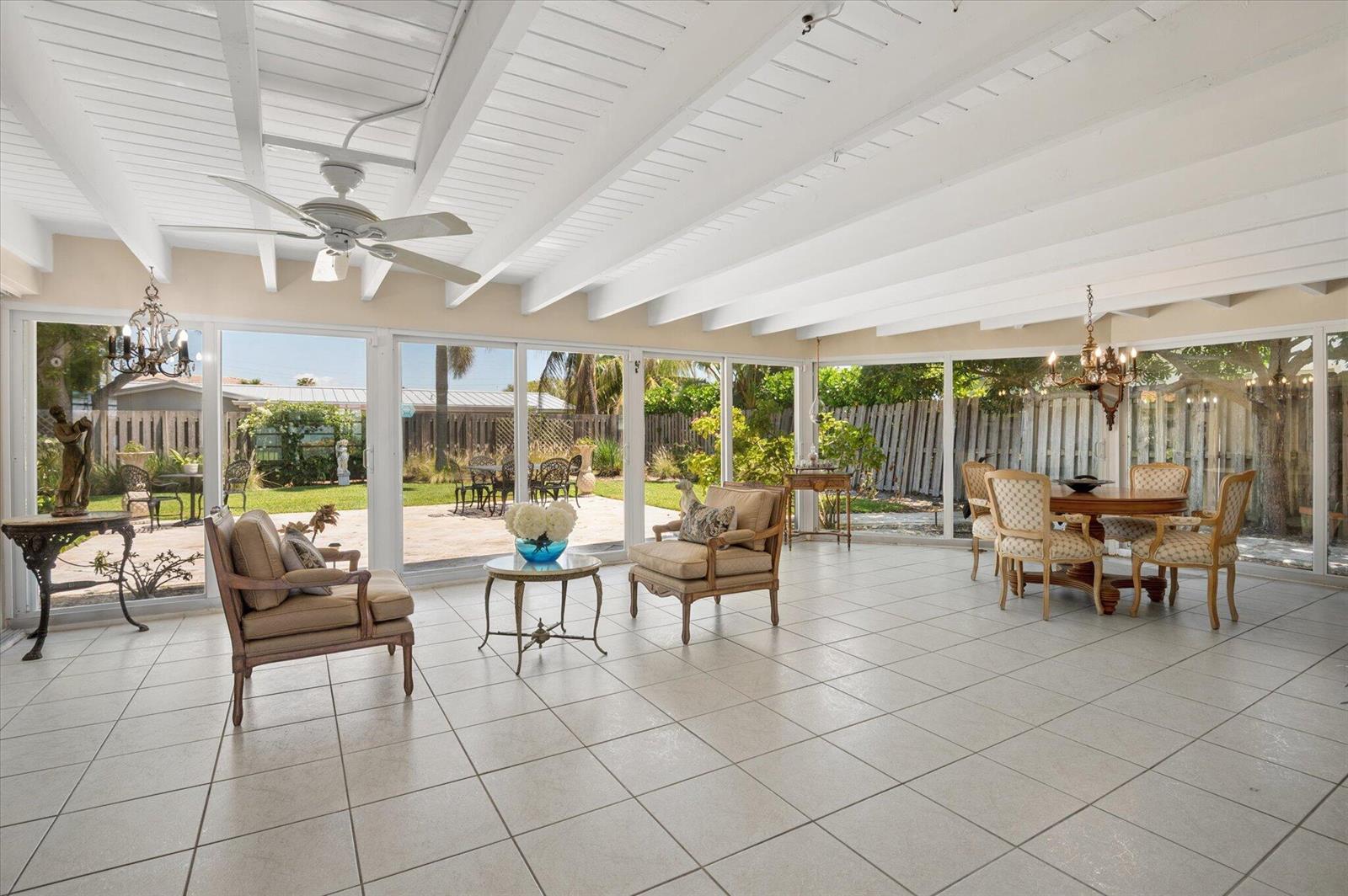 A sunroom with white beamed ceilings, tiled floors, and large glass walls overlooking a backyard — 611 SE 11th Street, Pompano Beach FL 33060, POMPANO BEACH, FL