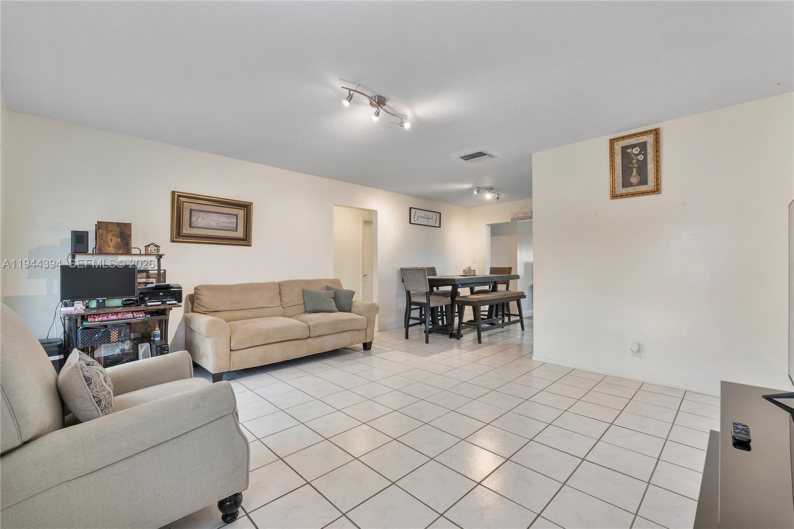 A dining room features a dark wooden table with upholstered chairs and tiled flooring — 5011 NW 51st St, Tamarac FL 33319, TAMARAC, FL