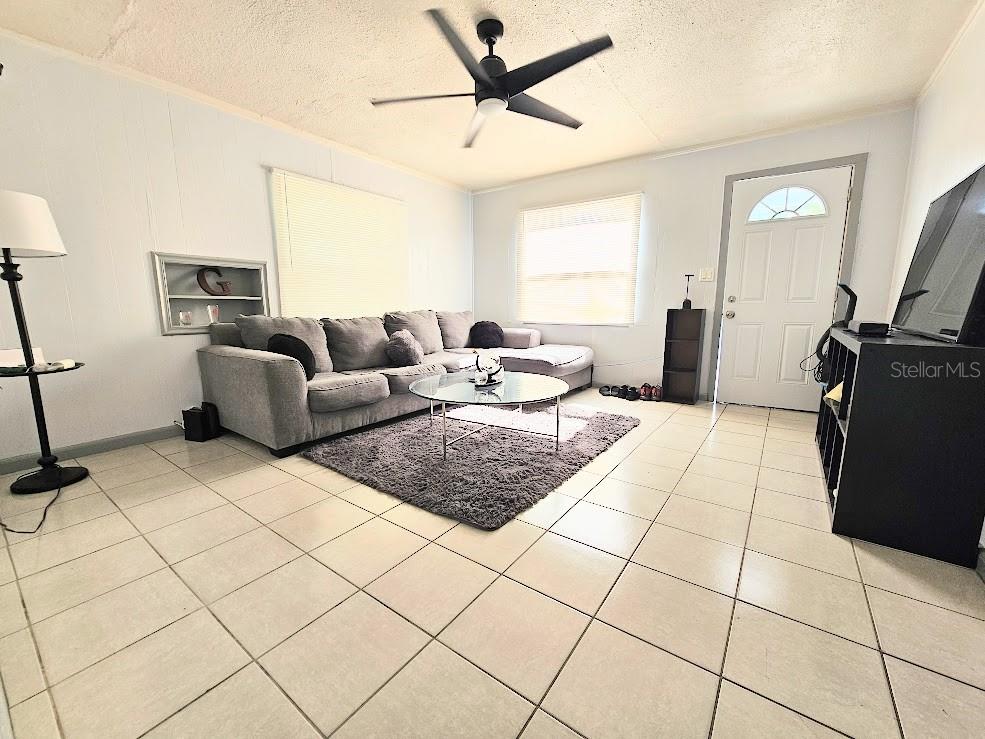A living room features light-colored tile flooring, a gray sectional sofa, and a ceiling fan — 1500 S MARTIN LUTHER KING JR AVENUE, CLEARWATER, FL