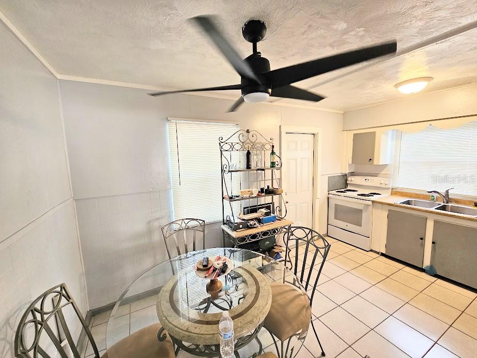 A kitchen and dining area with a glass table, metal chairs, and white tile flooring — 1500 S MARTIN LUTHER KING JR AVENUE, CLEARWATER, FL