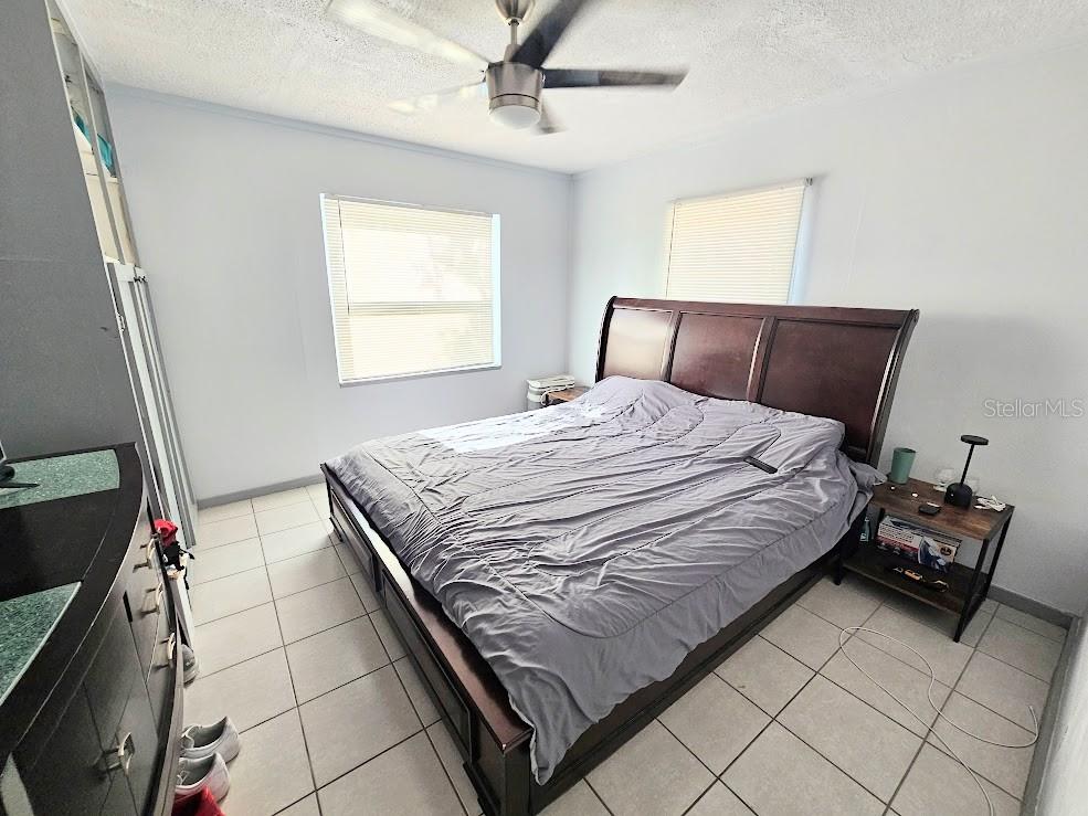 A bedroom features a dark wood bed frame, tile flooring, and a ceiling fan — 1500 S MARTIN LUTHER KING JR AVENUE, CLEARWATER, FL