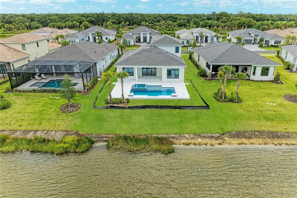 An aerial view of a suburban house with a swimming pool overlooking a lake — 4517 MONDRIAN COURT, SARASOTA, FL