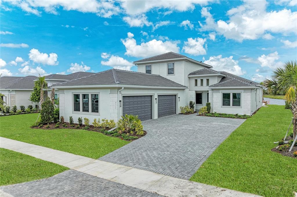 A two-story house with a gray tile roof, white stucco walls, and a paved driveway — 4517 MONDRIAN COURT, SARASOTA, FL