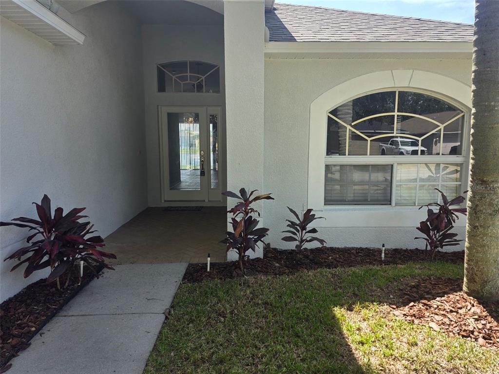 The exterior of a house features a covered entryway, a large arched window, and landscaping — 2313 LAWRENCE HALL STREET, RUSKIN, FL