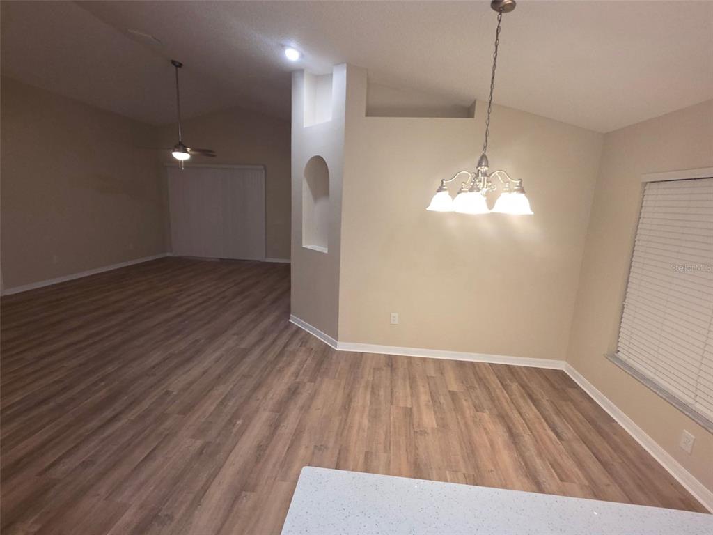 An open-concept dining area features wood-look flooring, a chandelier, and a view into the living room — 2313 LAWRENCE HALL STREET, RUSKIN, FL