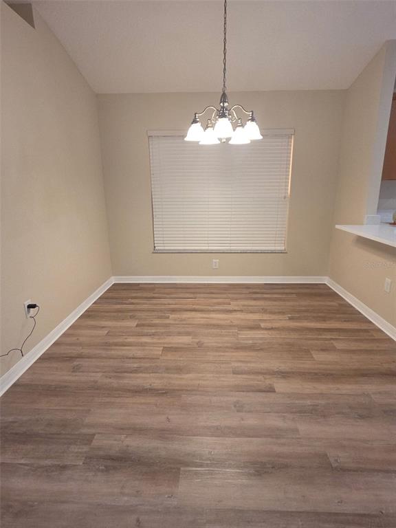 An empty dining area features light-colored walls, a chandelier, and wood-look flooring — 2313 LAWRENCE HALL STREET, RUSKIN, FL