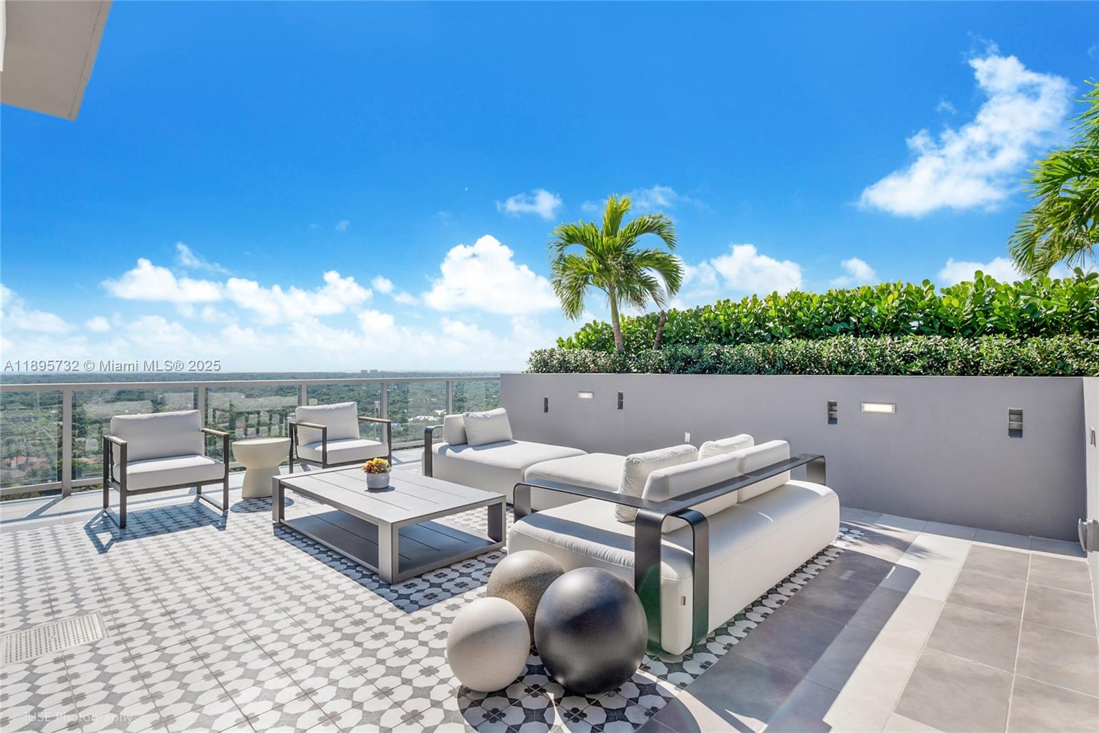 An outdoor rooftop terrace features modern white furniture, decorative spheres, and a glass railing — 9600 S Dixie Hwy # A15, Miami FL 33156, MIAMI, FL
