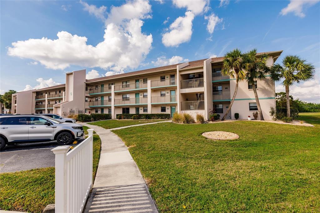 A multi-story apartment building with balconies and a sidewalk leading to the entrance — 175 KINGS HIGHWAY UNIT 538, PUNTA GORDA, FL