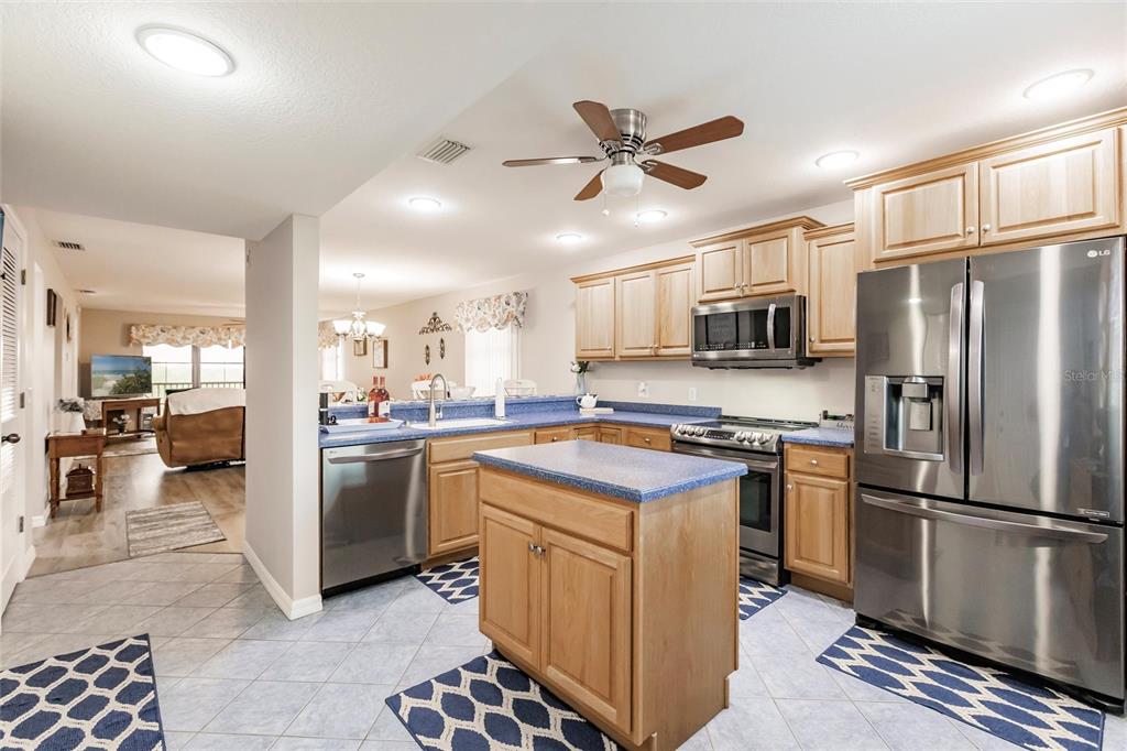 A kitchen with light wood cabinets, blue countertops, stainless steel appliances, and a central island — 175 KINGS HIGHWAY UNIT 538, PUNTA GORDA, FL