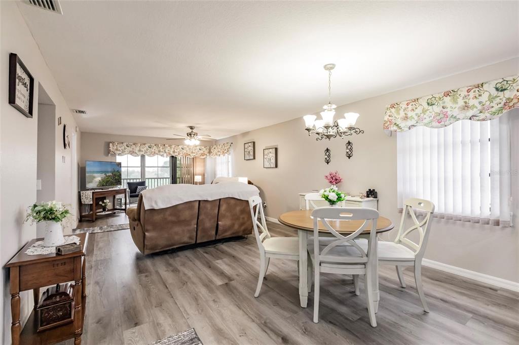 An open-concept living and dining area features wood-look flooring, a chandelier, and a brown sofa — 175 KINGS HIGHWAY UNIT 538, PUNTA GORDA, FL