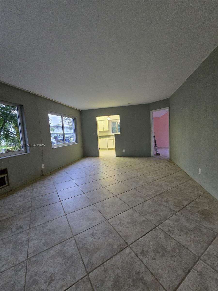 An empty living room features gray walls, large windows, and light-colored square floor tiles — 3201 SE 12th St # B3, Pompano Beach FL 33062, POMPANO BEACH, FL