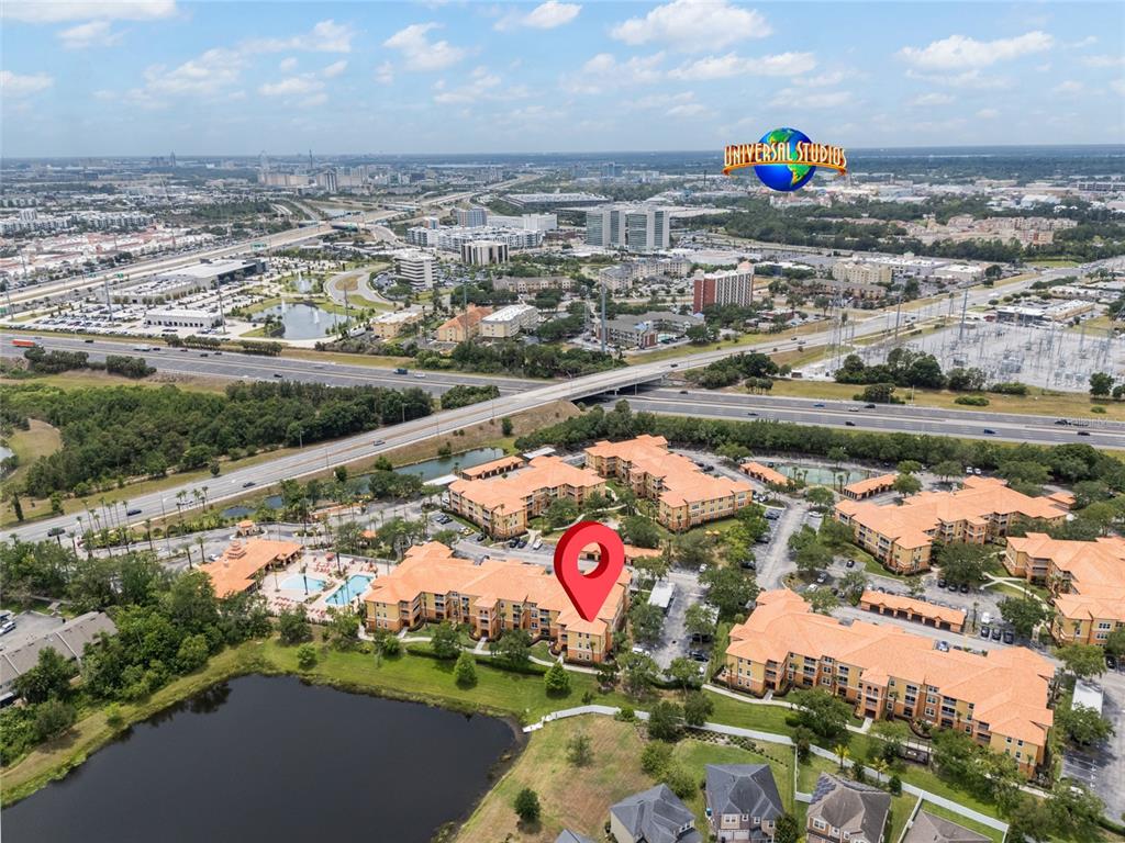 An aerial view shows a multi-story apartment complex with orange roofs near a highway — 5447 VINELAND ROAD UNIT 1308, ORLANDO, FL