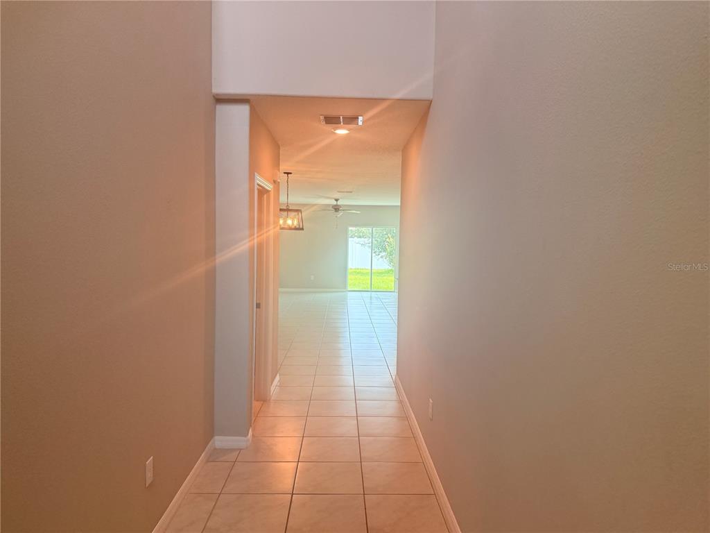 A tiled hallway leads to an open living area with a sliding glass door — 10363 SHADY PRESERVE DRIVE, RIVERVIEW, FL