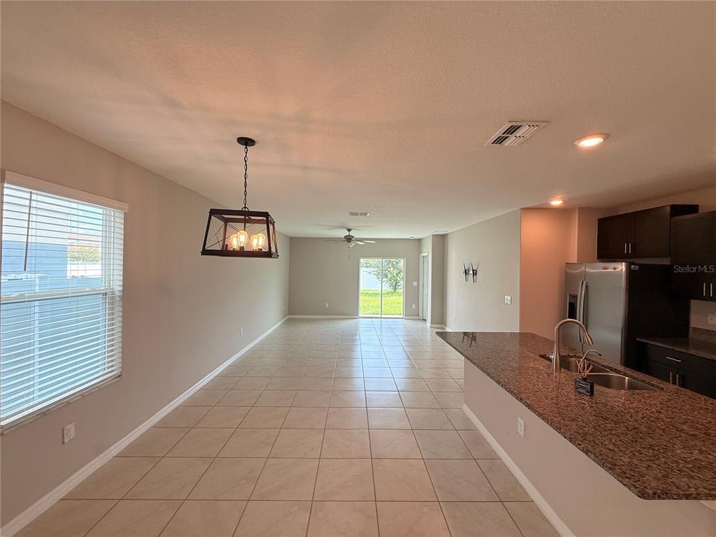An open-concept kitchen and dining area features tile flooring, granite countertops, and a pendant light — 10363 SHADY PRESERVE DRIVE, RIVERVIEW, FL