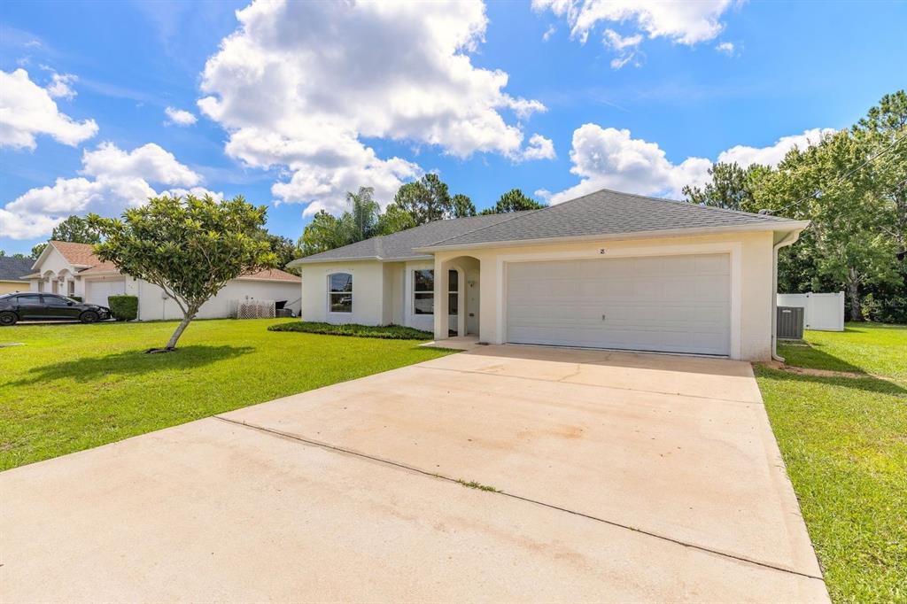 A single-story house with a white exterior, a two-car garage, and a concrete driveway — 18 LEE DRIVE, PALM COAST, FL