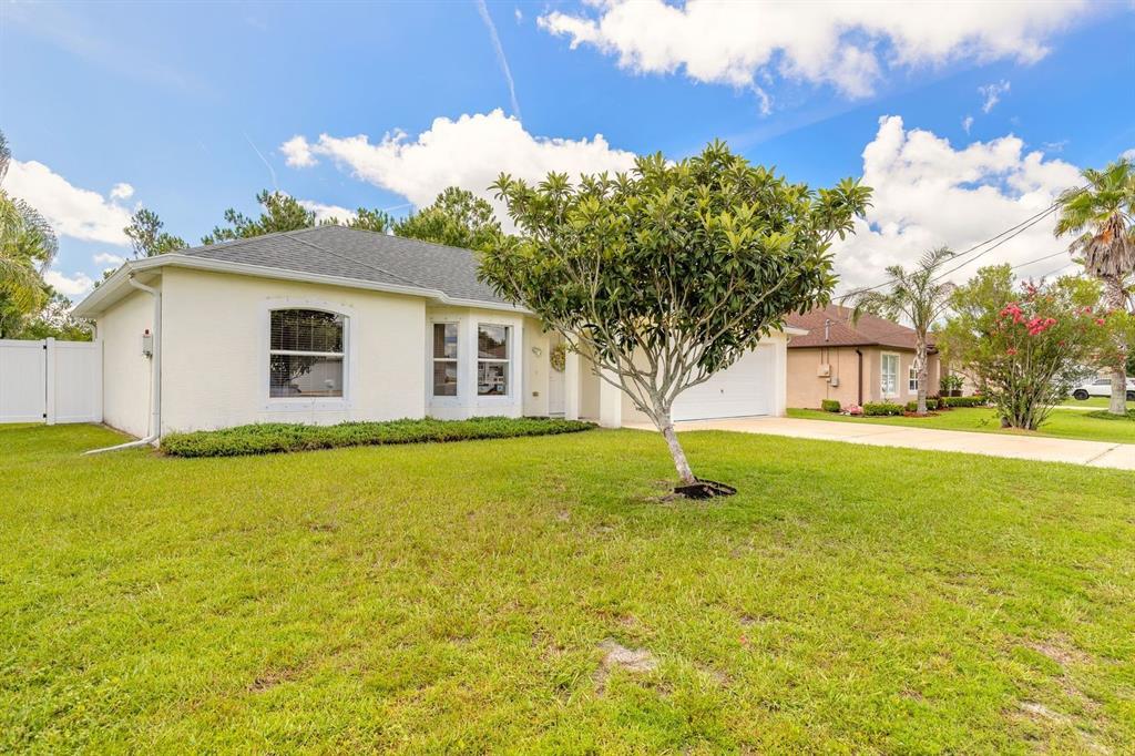 A single-story house with a light-colored exterior, a front lawn, and a central tree — 18 LEE DRIVE, PALM COAST, FL