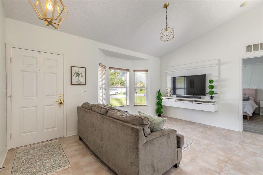 A living room features a gray sofa, a wall-mounted television, and tile flooring — 18 LEE DRIVE, PALM COAST, FL