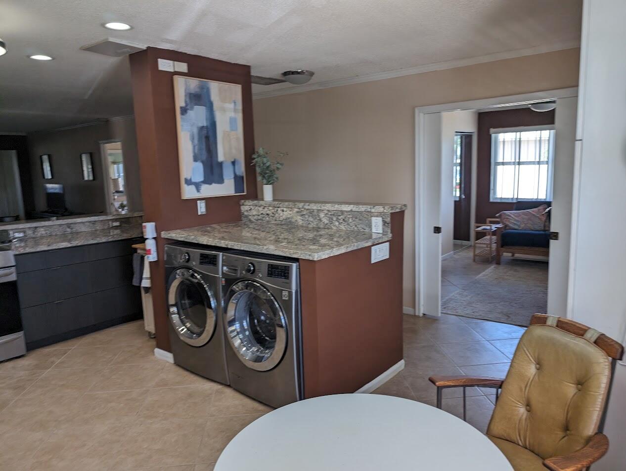 A laundry area with stainless steel appliances and a granite countertop sits in an open room — 1710 NW 18th Avenue # 204, Delray Beach FL 33445, DELRAY BEACH, FL