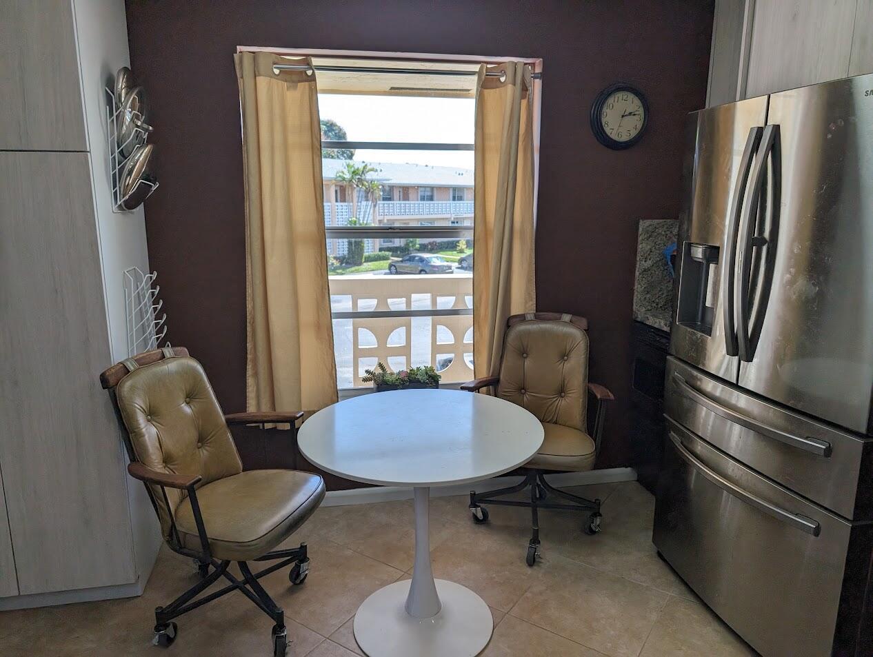 A small kitchen dining area features a white pedestal table, two rolling chairs, and a window — 1710 NW 18th Avenue # 204, Delray Beach FL 33445, DELRAY BEACH, FL
