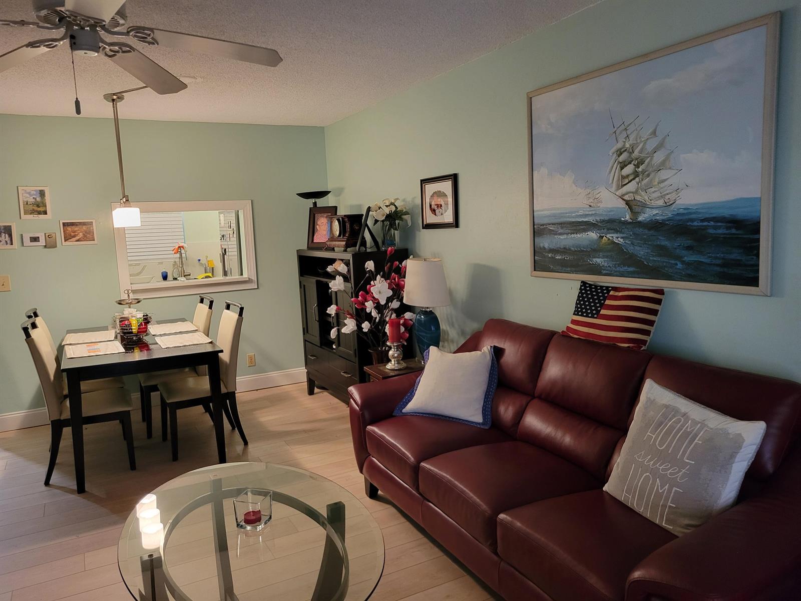 A living room with a red leather sofa, a glass coffee table, and a dining area — 700 Lori Drive # 203, Palm Springs FL 33461, PALM SPRINGS, FL