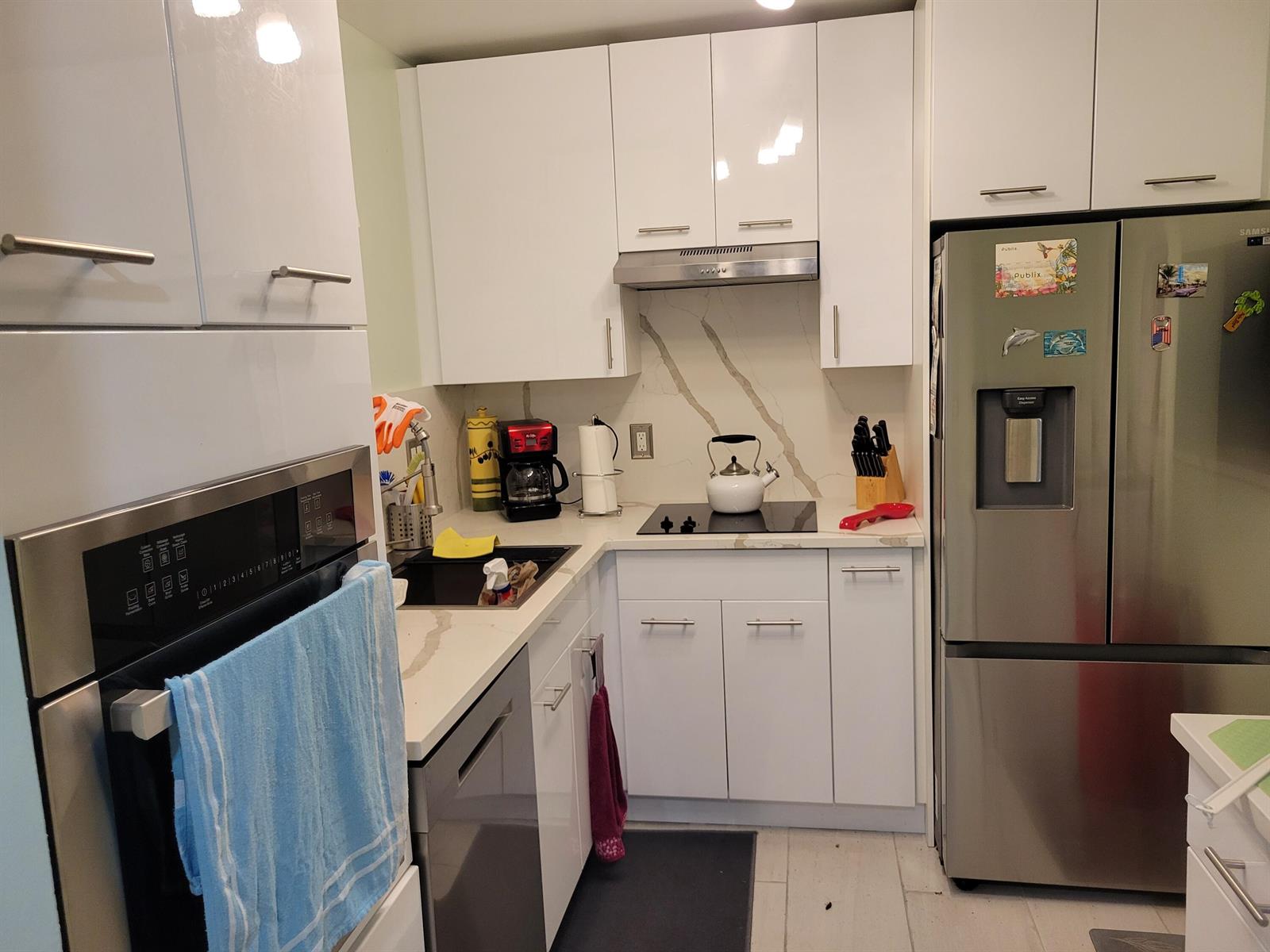 A modern kitchen features white cabinets, stainless steel appliances, and a marble-patterned backsplash — 700 Lori Drive # 203, Palm Springs FL 33461, PALM SPRINGS, FL