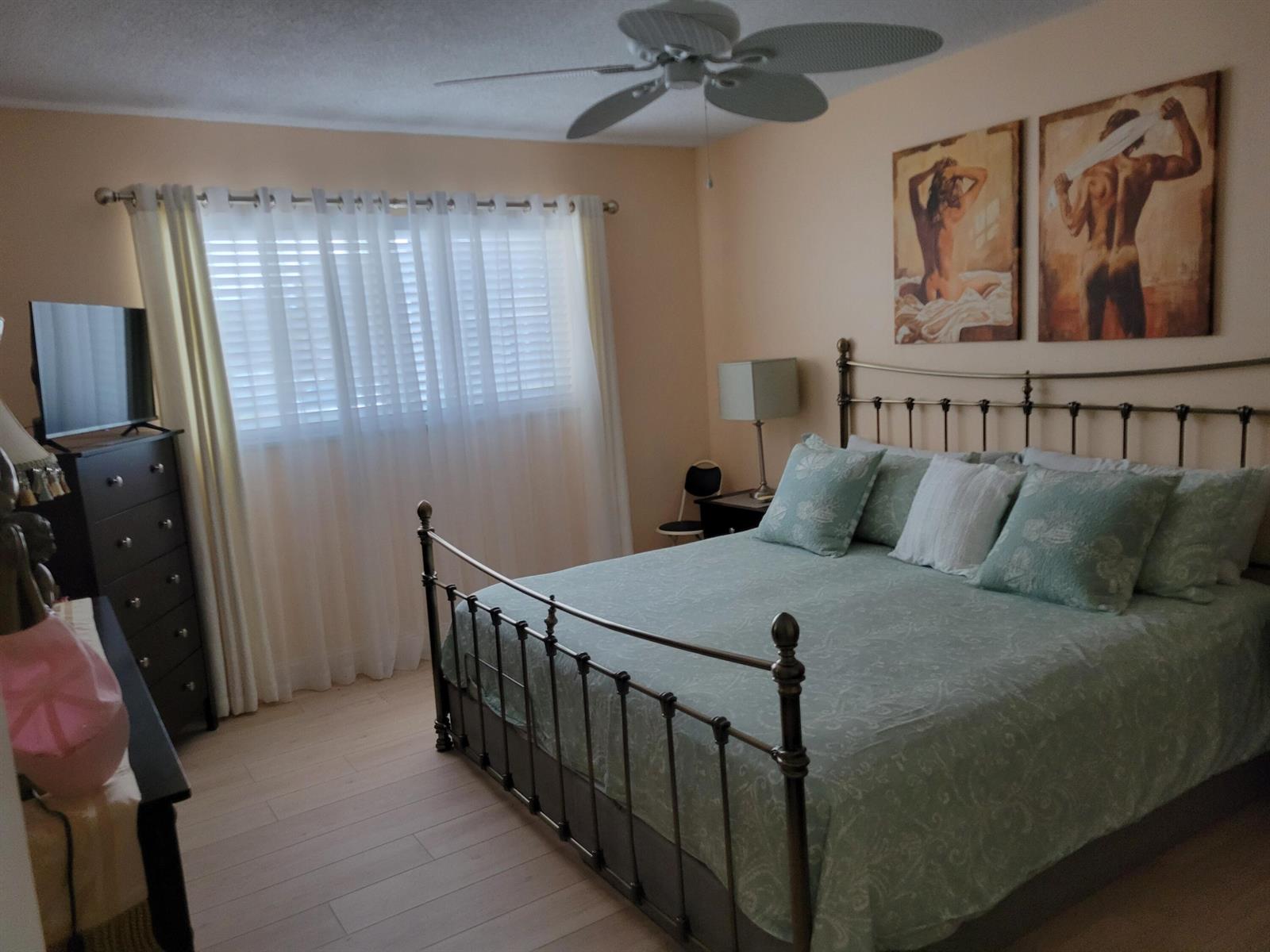 A bedroom features a metal bed frame, light-colored flooring, a dresser, and two wall paintings — 700 Lori Drive # 203, Palm Springs FL 33461, PALM SPRINGS, FL