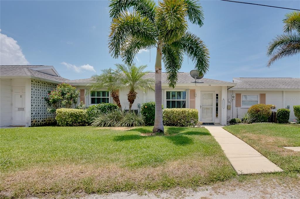 A single-story house with a white facade, a palm tree, and a concrete walkway — 112 THE CORSO UNIT 112, VENICE, FL
