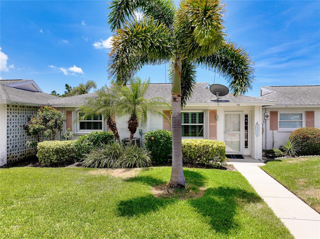 A single-story house with a palm tree in the front yard and a walkway — 112 THE CORSO UNIT 112, VENICE, FL