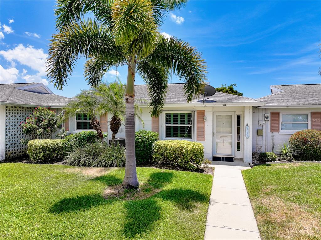 A single-story house with a white exterior, a palm tree, and a concrete walkway — 112 THE CORSO UNIT 112, VENICE, FL