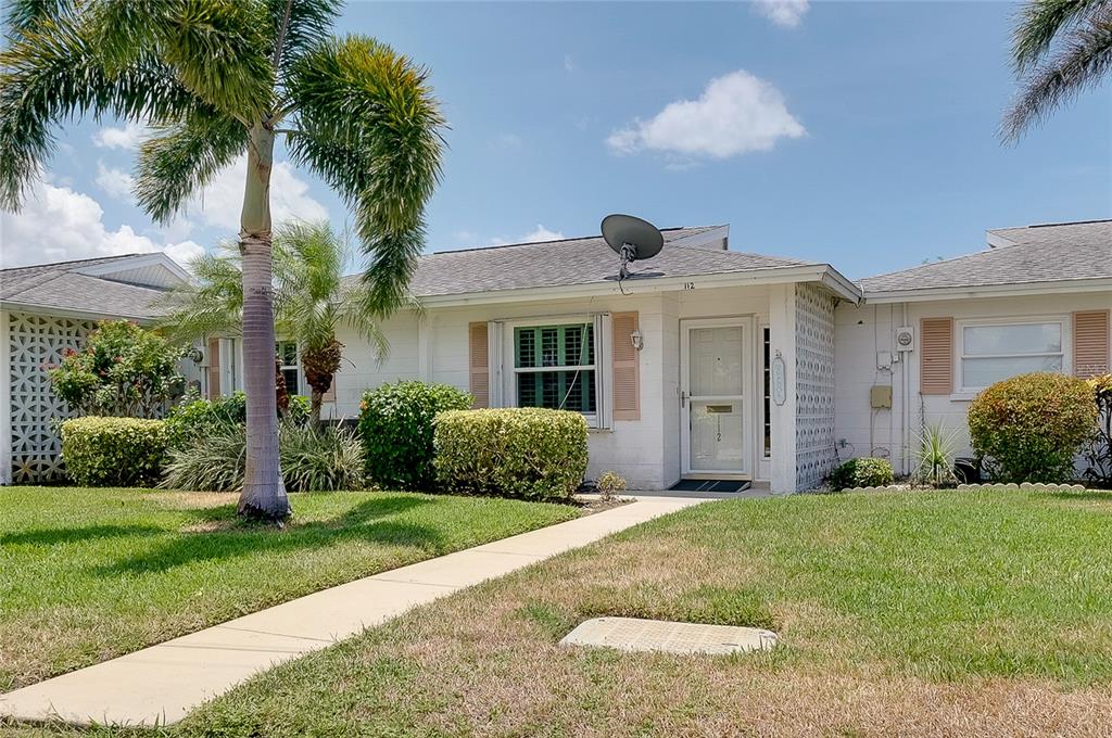 A single-story white house with a palm tree, a front walkway, and a satellite dish — 112 THE CORSO UNIT 112, VENICE, FL